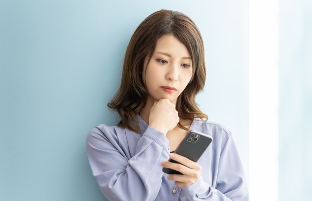 不安げにスマホをみる女性